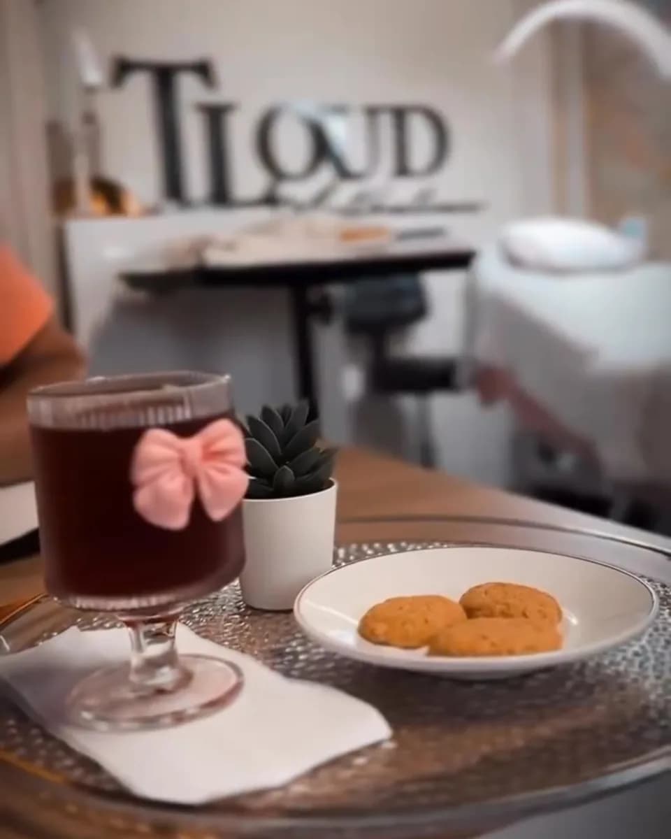 Bebida y galletas de cortesía con el letrero de TLOUD Aesthetics al fondo